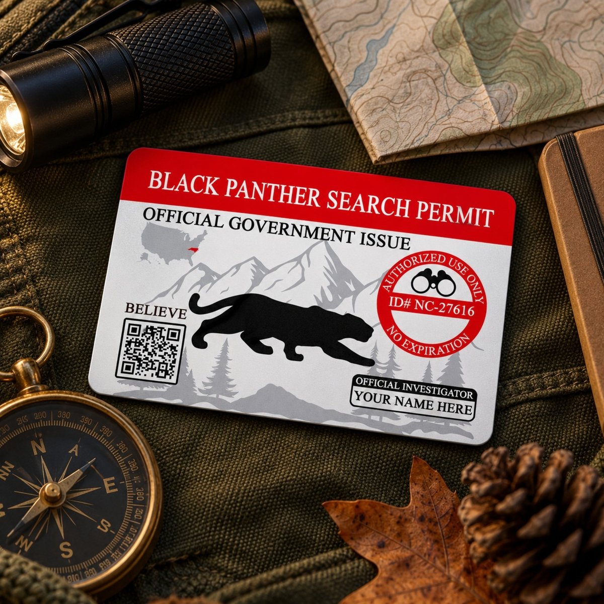 a Black Panther Search Permit card, which is an official government document, placed on a surface with various other items such as a compass, a map, and a pine cone.