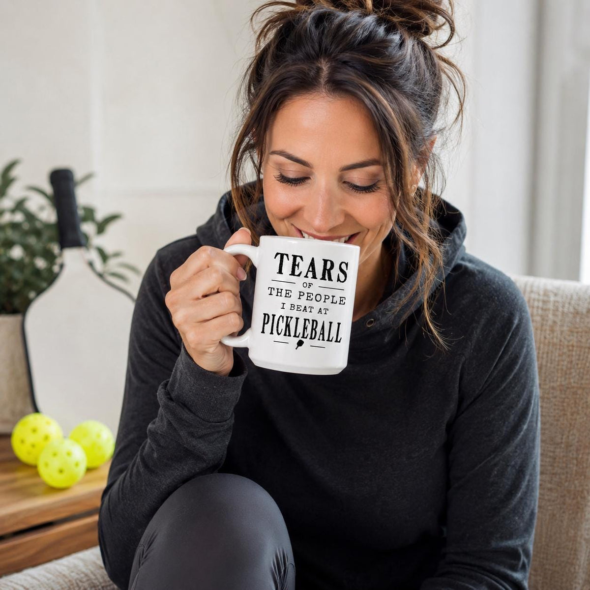 Woman relaxing on a couch with a white mug reading Tears of the people I beat at pickleball