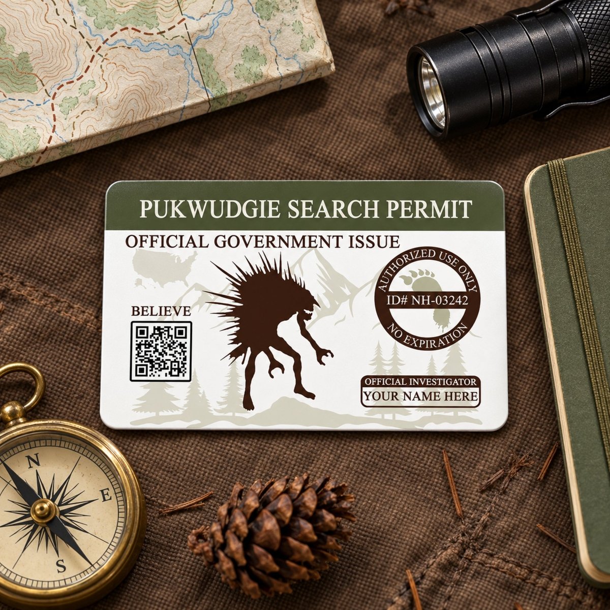 a Pukwidgee search permit, a compass, a magnifying glass, and some pine cones, all arranged on a table.