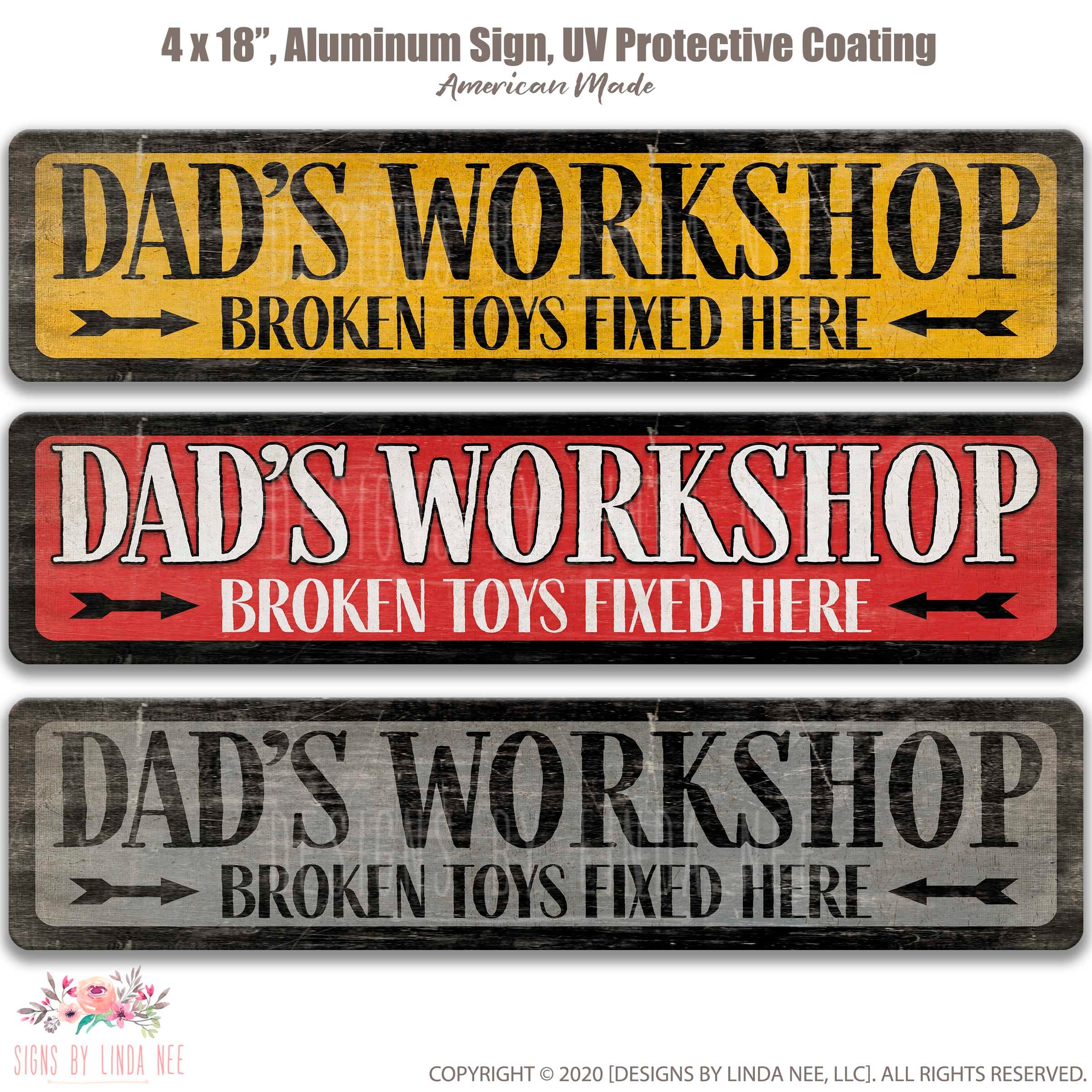 three signs that say "DAD'S WORKSHOP BROKEN TOYS FOUNDED HERE" in different colors and styles.