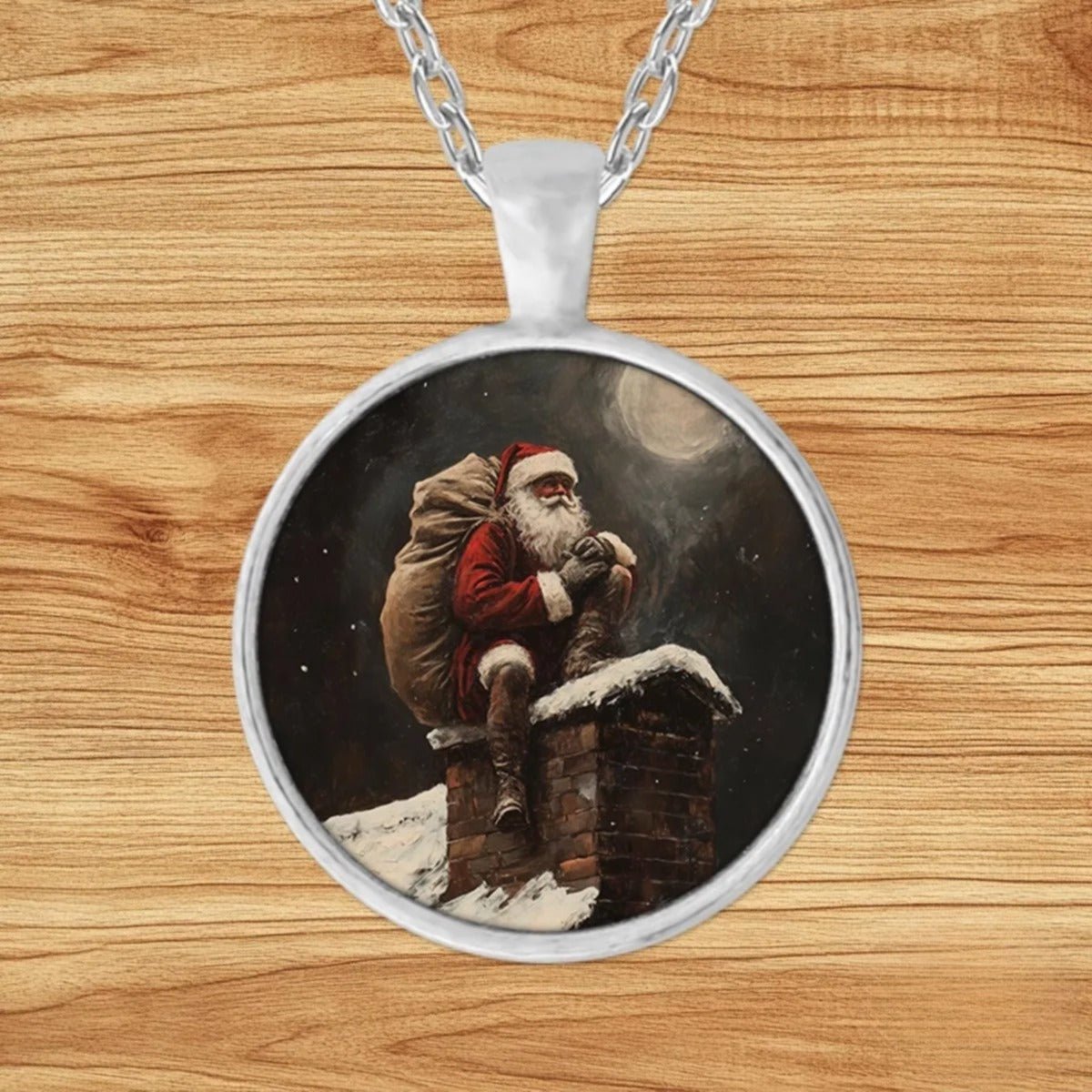 Round silver charm pendant necklace featuring Santa Claus perched atop a snowy chimney with his sack of gifts beneath a full moon