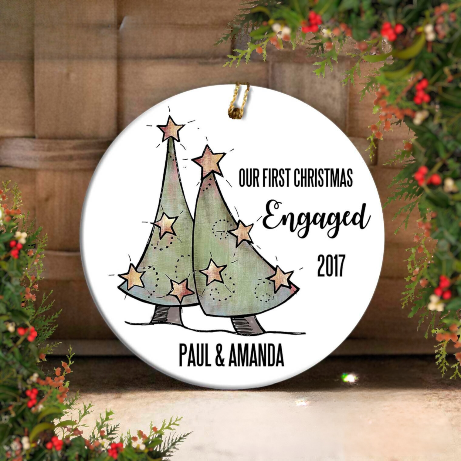 Christmas ornament with two trees and text 'Our First Christmas Engaged 2017 Paul & Amanda' on a white background.