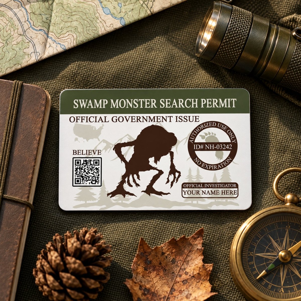 a Swamp Monster Search permit card, a compass, a magnifying glass, a pine cone, and a leaf, all arranged on a surface.