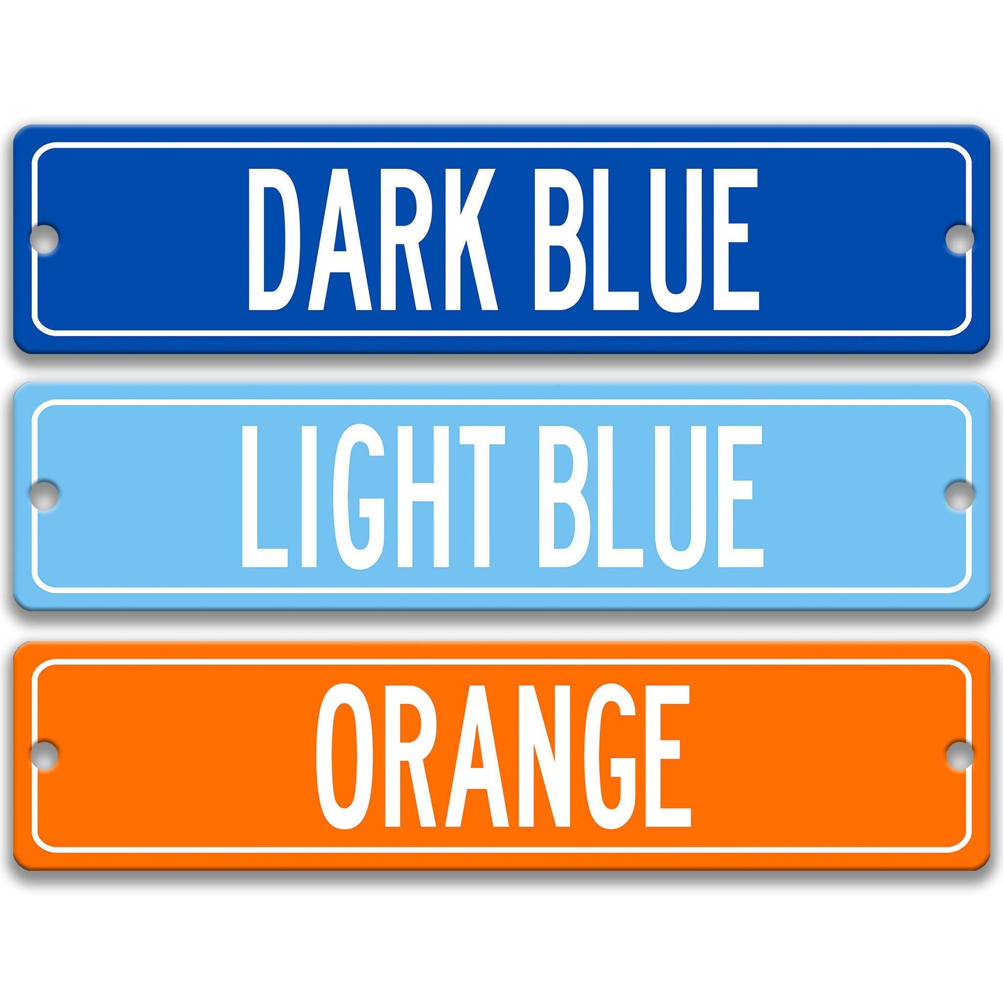 three rectangular street signs in different colors: dark blue, light blue, and orange.