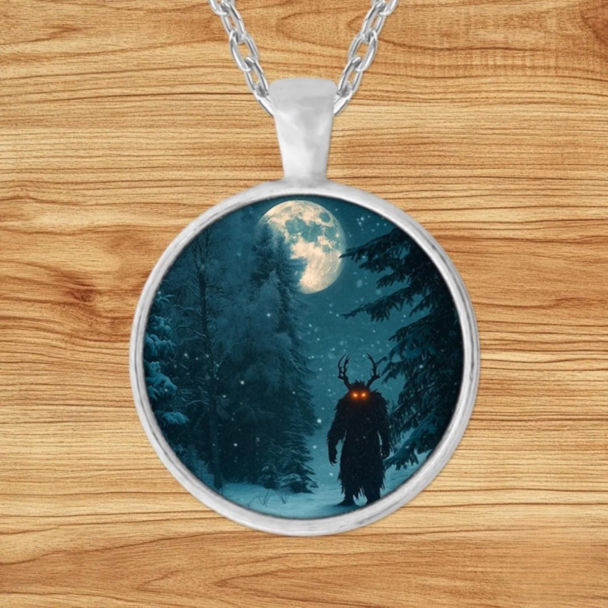 Round silver charm pendant necklace featuring a horned silhouette with glowing red eyes standing in a moonlit snowy forest