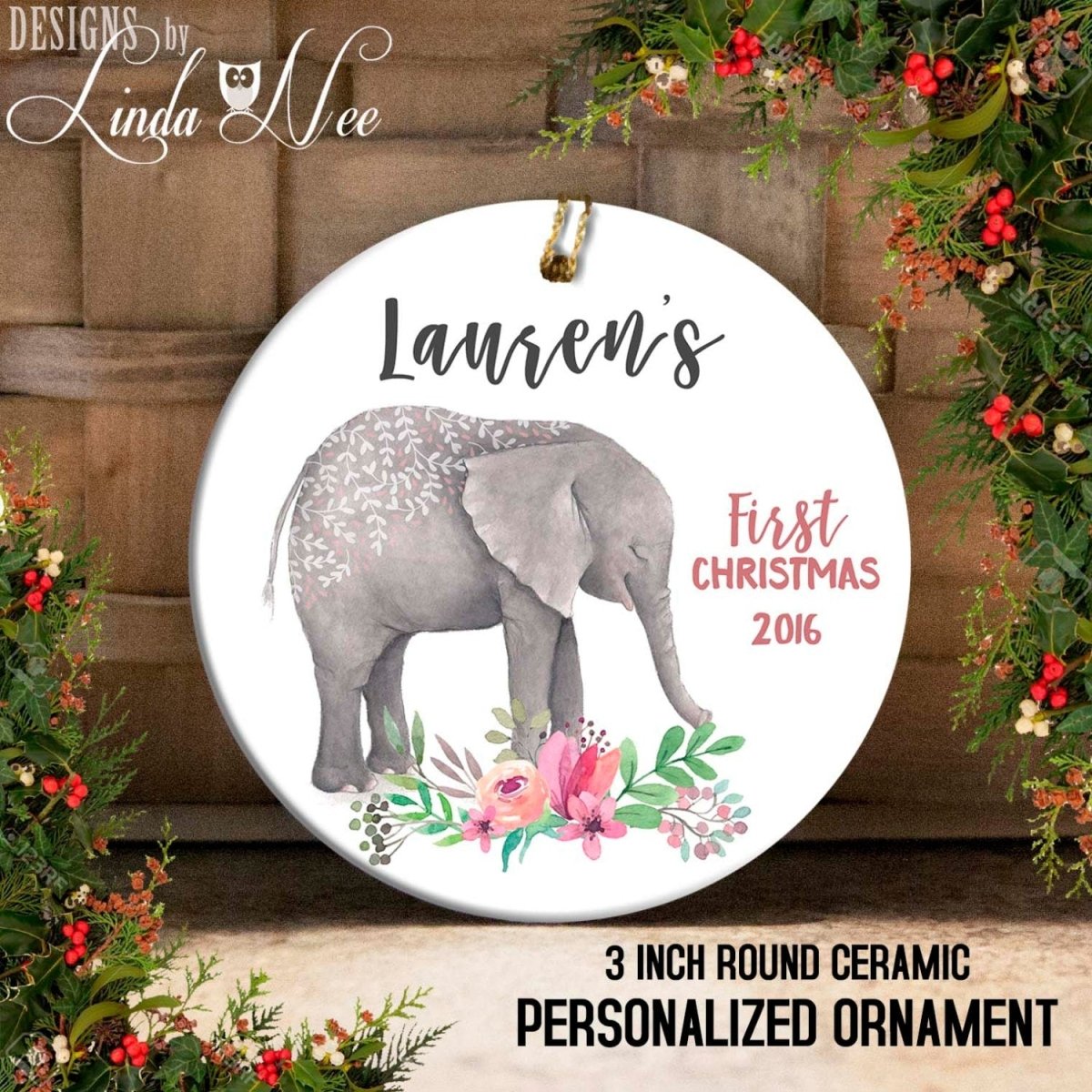 A round ceramic ornament featuring an elephant surrounded by flowers and greenery. The ornament has the text "Lauren's First Christmas 2016" and "3 INCH ROUND CERamic PERSONALIZED ORNAMENT" printed on it.