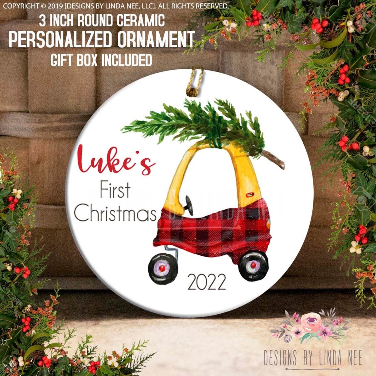 A ceramic ornament in the shape of a toy car, decorated with a Christmas tree and a plaid blanket, with the text "Luke's First Christmas" and the year "2022" printed on it.