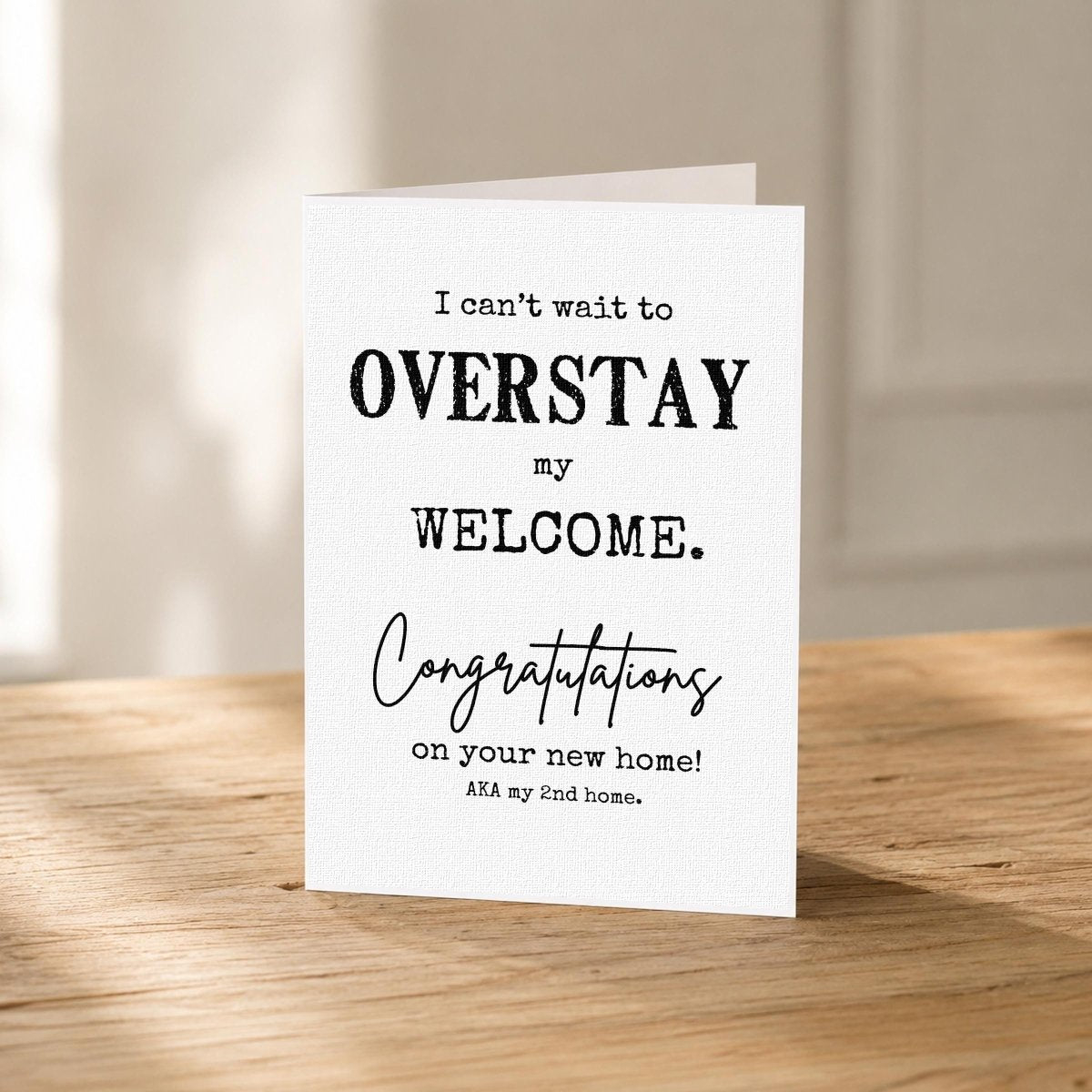 Close-up of the Overstay My Welcome Funny New Home Card showing the distressed black typography.