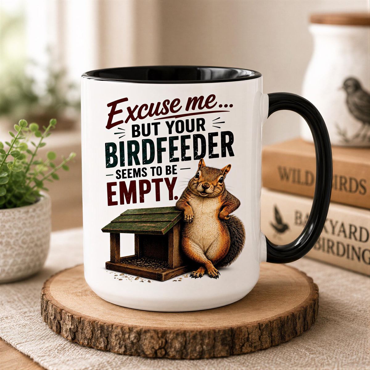 Black handle squirrel mug on a wood slice coaster beside backyard birding books, a small plant and a bird jar