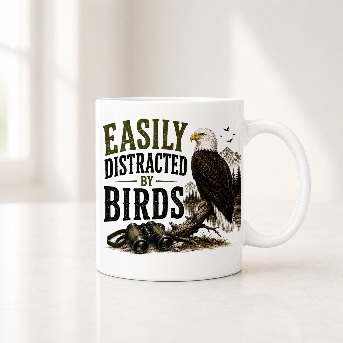 White Easily Distracted by Birds mug with a bald eagle perched on a log above binoculars and misty peaks