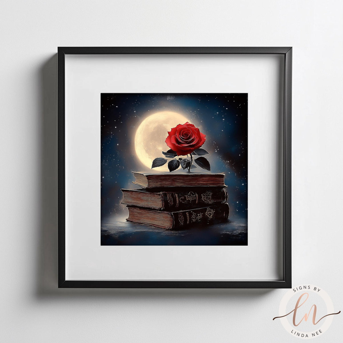 Framed art print featuring a red rose resting on a stack of old books against a night sky with a large full moon. The artwork is presented in a black frame with a white mat, mounted on a light gray wall.