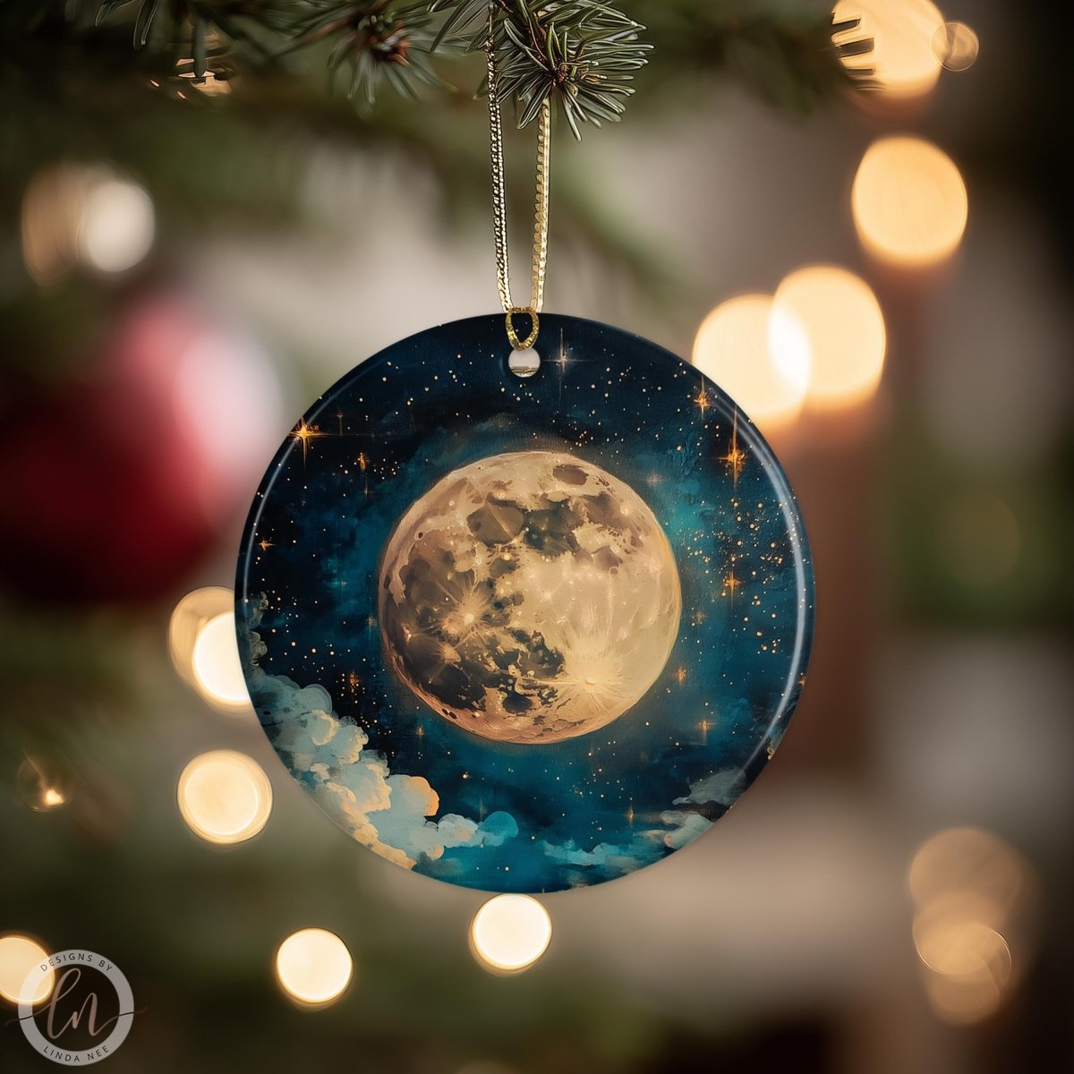A round ornament with a moon and stars design hangs from a tree branch, surrounded by twinkling lights.