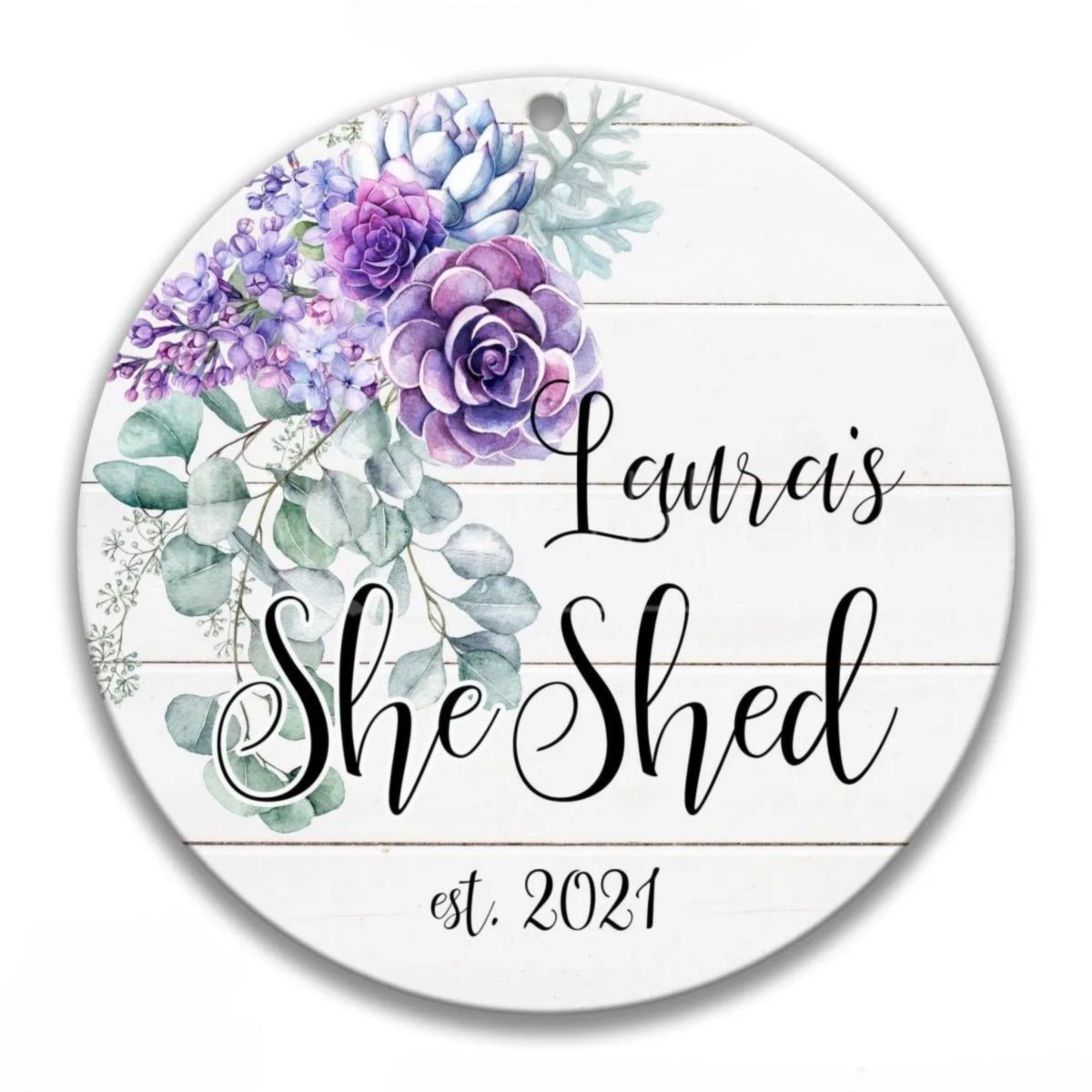A round white ornament with a floral design and the text "Lauren's She Shed est. 2021" printed on it.