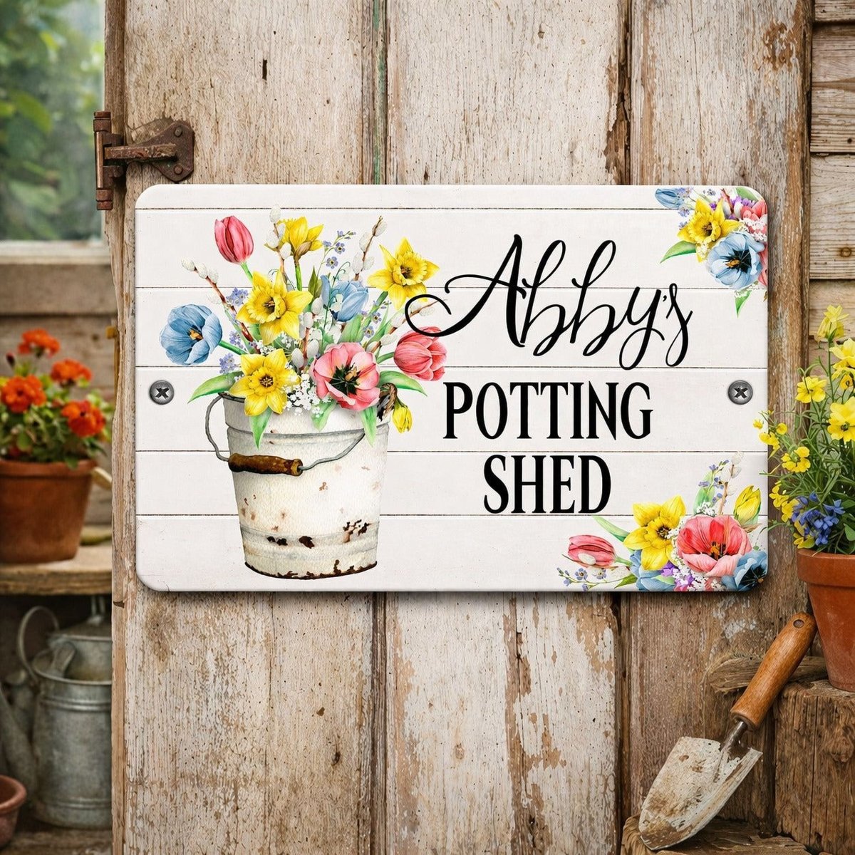 A white sign with a bucket of colorful flowers and the text "Abby's POTTING SHED" is displayed on a wooden door.