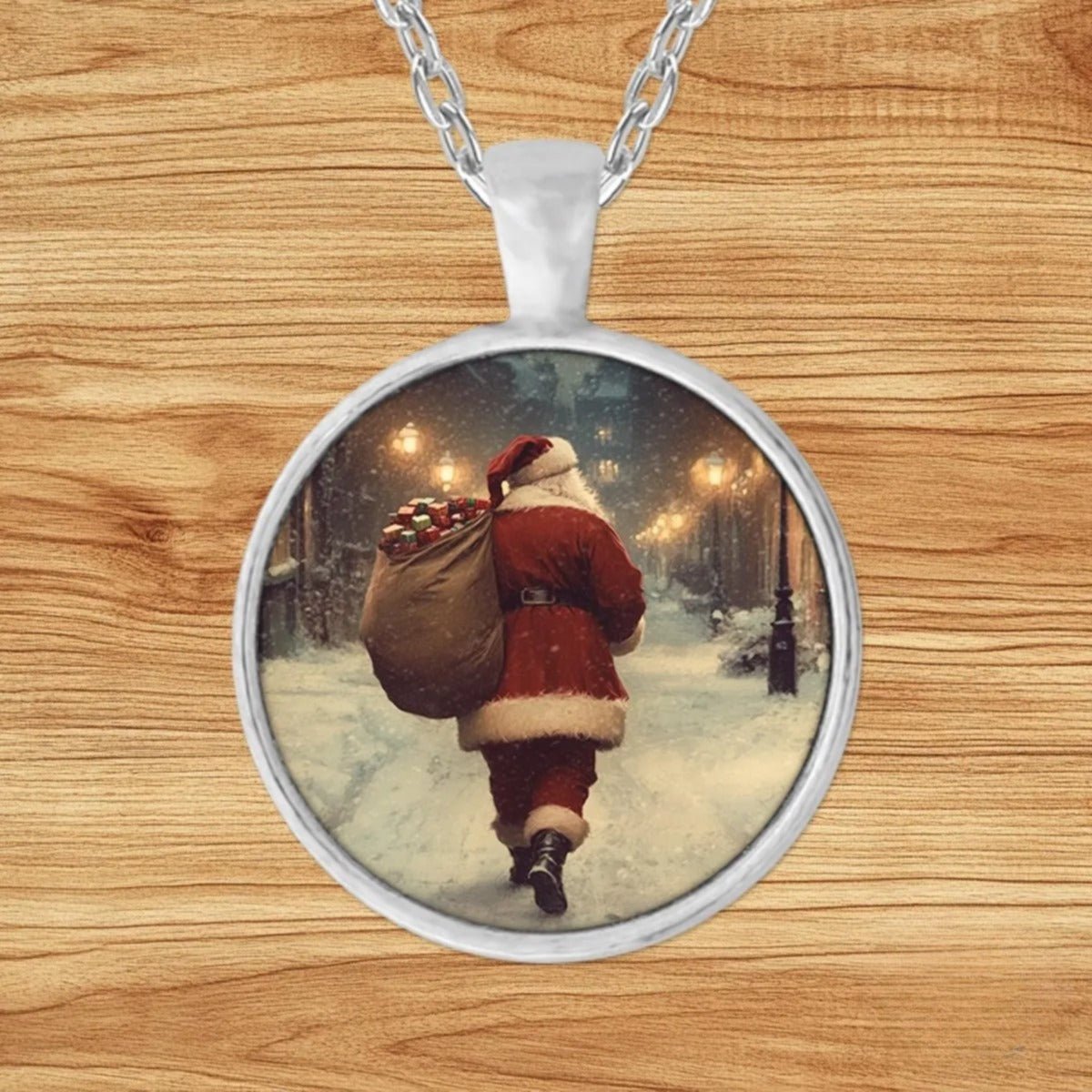 Round silver charm pendant necklace featuring Santa walking down a snowy cobblestone village street at night with a sack of presents