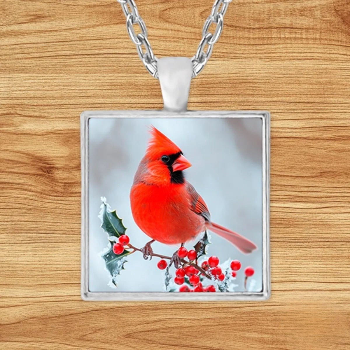 Square silver charm pendant necklace featuring a red cardinal perched on a snow-dusted branch with winter berries