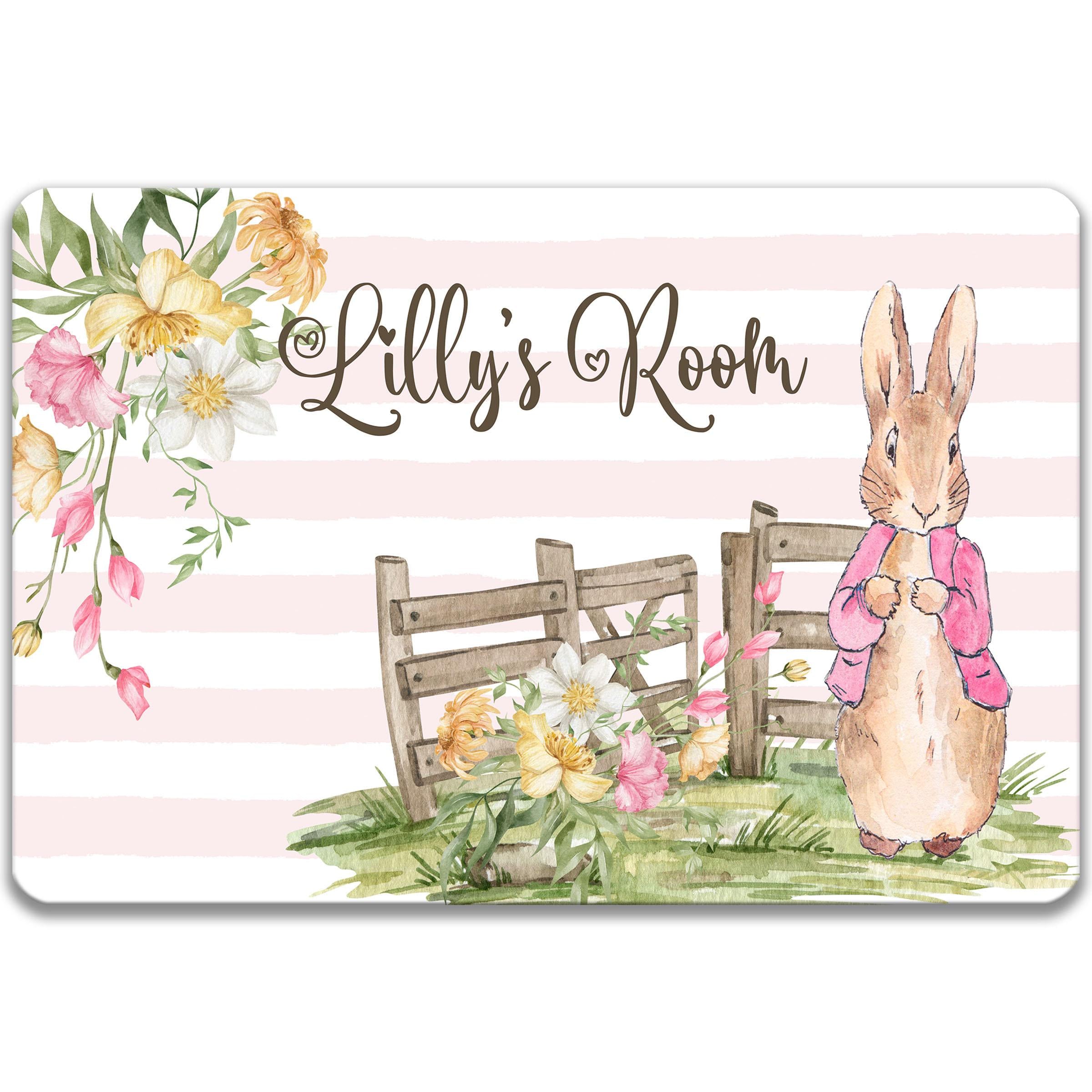 A watercolor illustration of a bunny rabbit wearing a pink sweater, standing in front of a wooden gate with flowers, and the text "Lilly's Room" written above it.