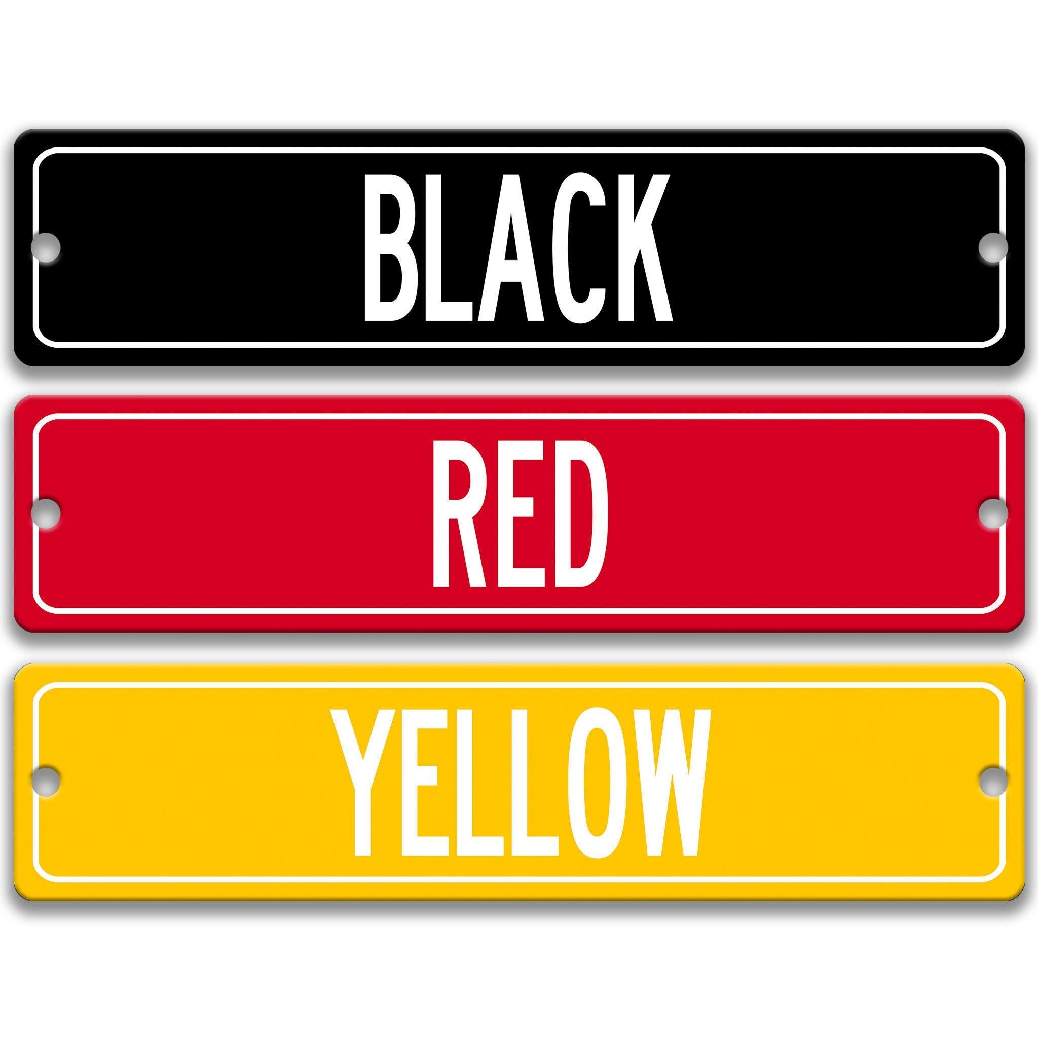 three rectangular street signs in different colors: black, red, and yellow.