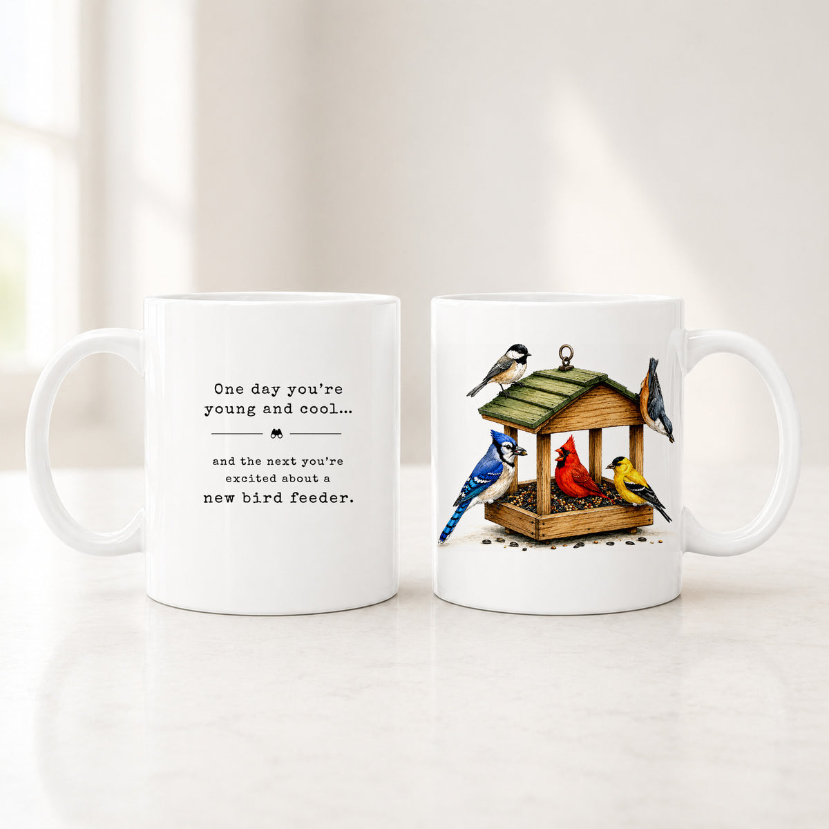 Both sides of the 11 oz white bird feeder mug, a cardinal, blue jay and goldfinch at a feeder beside the quote