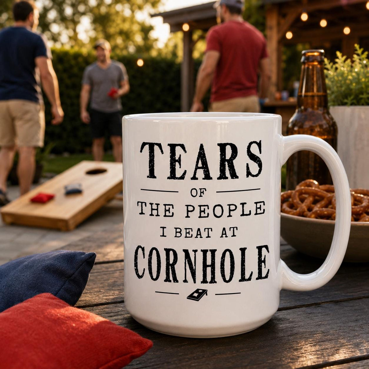 Cornhole mug on a wooden table with a bowl of pretzels and a red bean bag nearby
