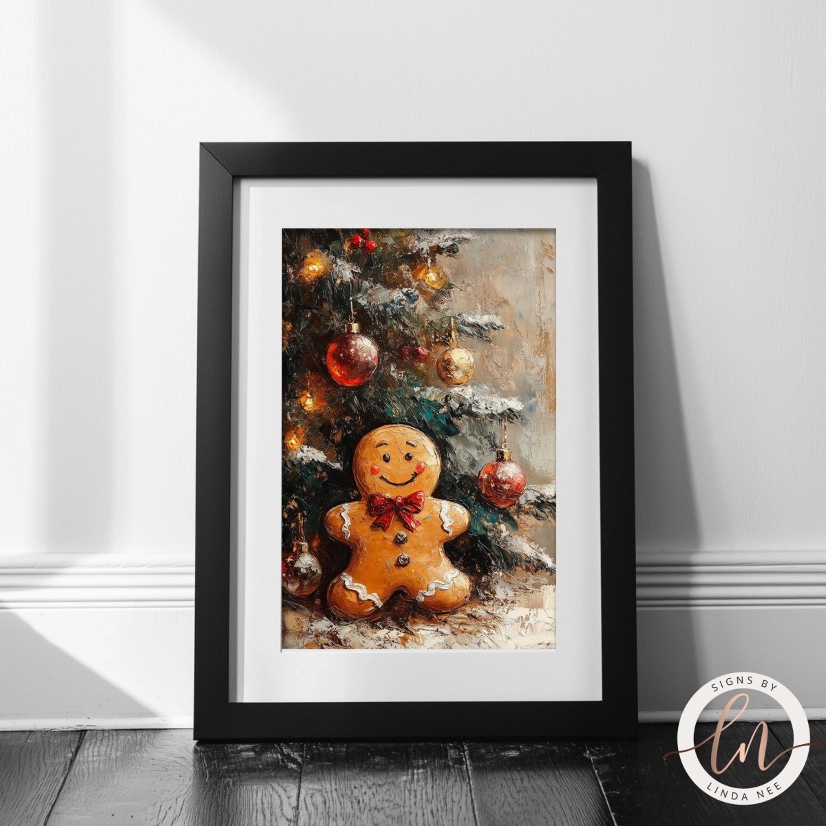 A framed painting depicting a gingerbread man sitting in front of a Christmas tree decorated with ornaments.