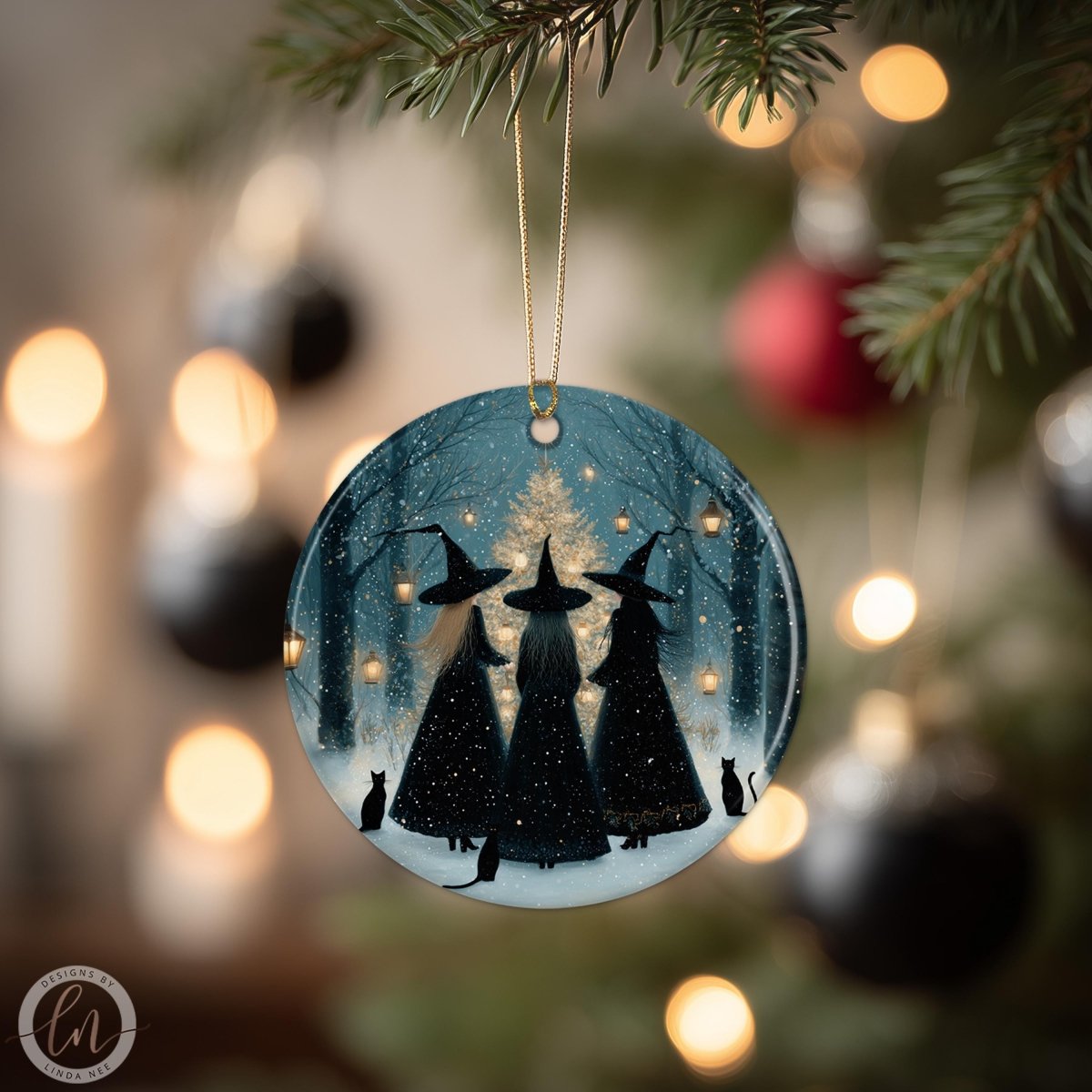 A round ornament featuring three black-haired women in witch's hats, silhouetted against a snowy forest scene, with a cat in the background, all illuminated by twinkling lights.