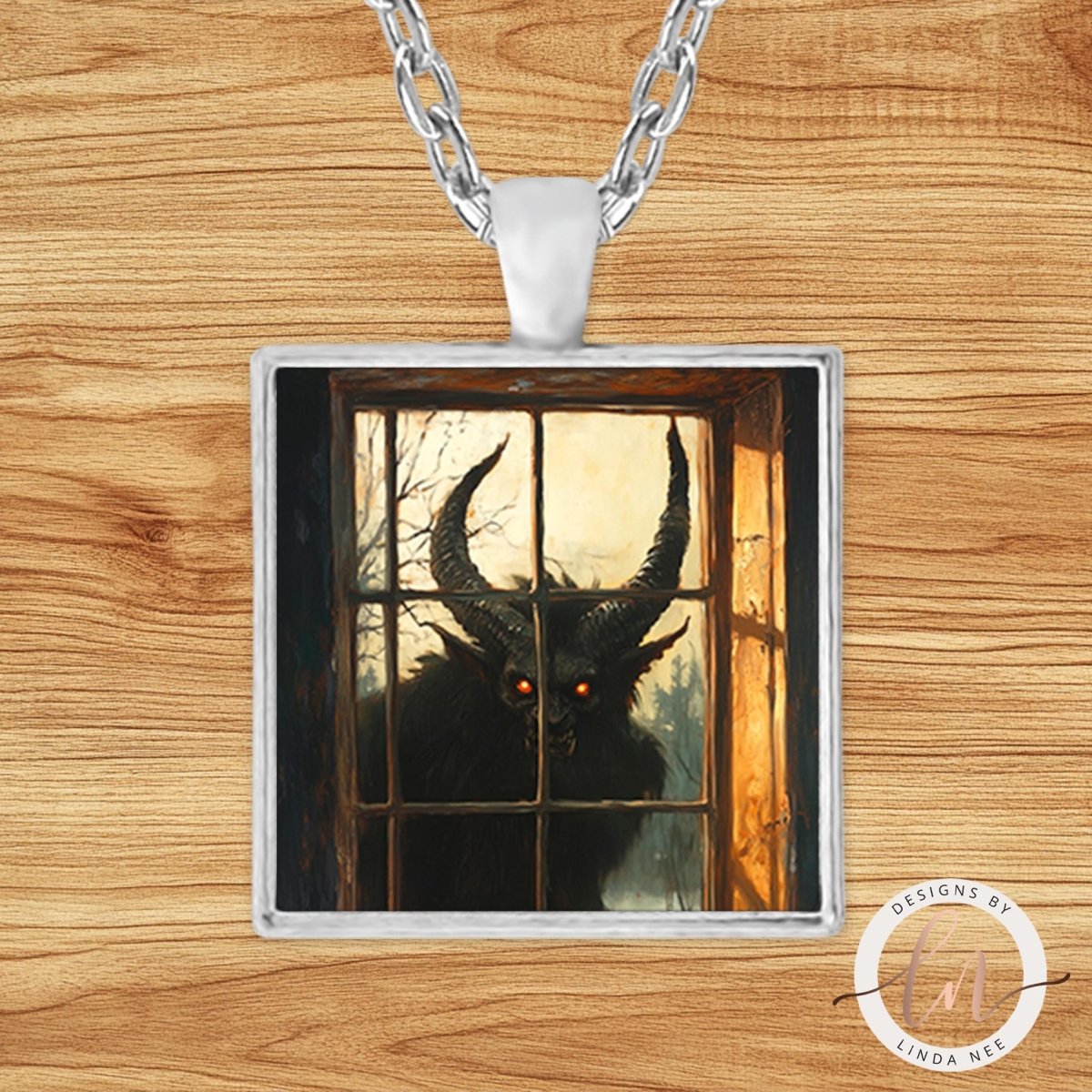 A pendant necklace with a square glass frame containing an image of a horned creature, possibly a monster or a demon, peering through a window.
