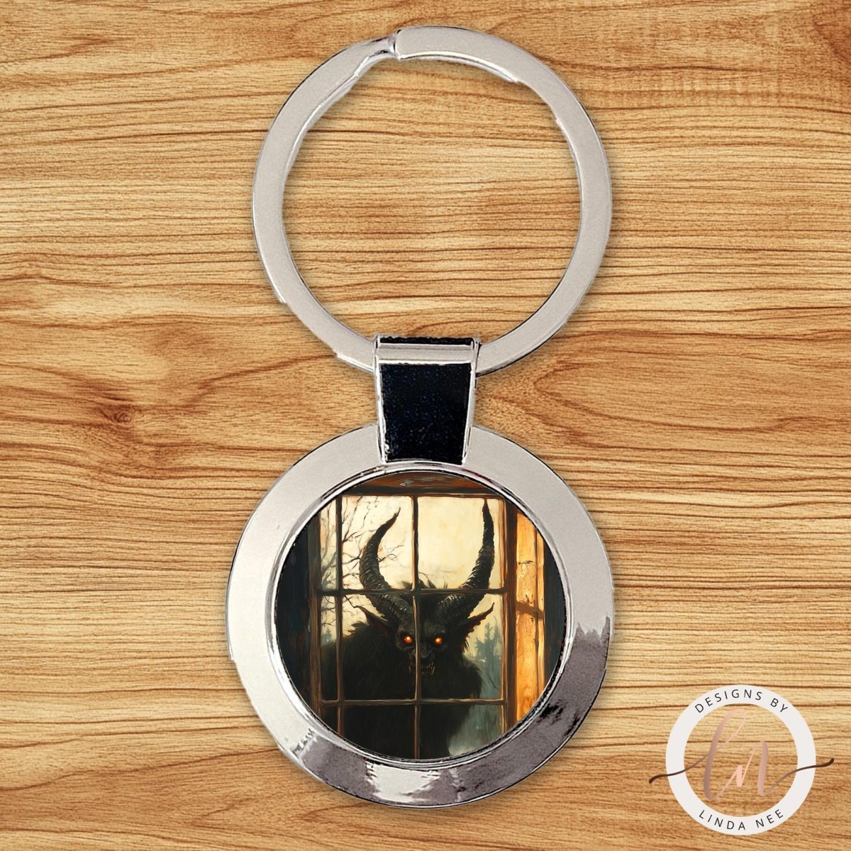 A keychain with a circular design featuring a silhouette of a horned creature, possibly a dragon or a monster, peering through a window.