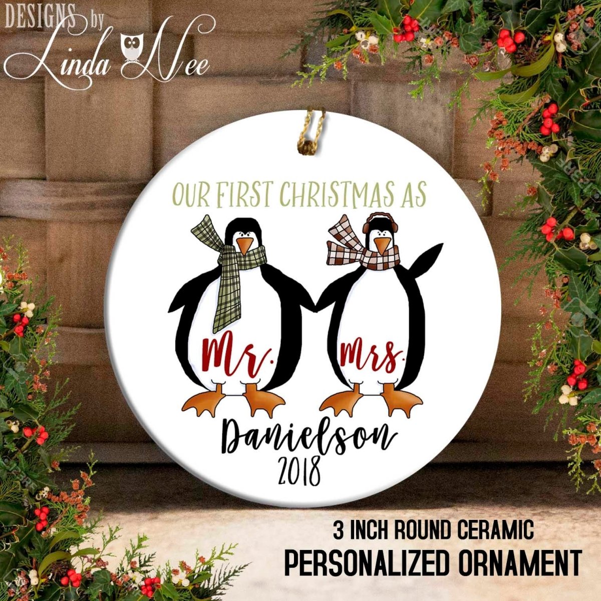 A round ceramic ornament with a couple of penguins, one wearing a scarf and the other a scarf with the text "Mr. Danielson 2018". The ornament is personalized and has the text "OUR FIRST CHRISTMAS AS" and "3 INCH ROUND CERamic PERSONALIZED ORNAMENT" printed on it.