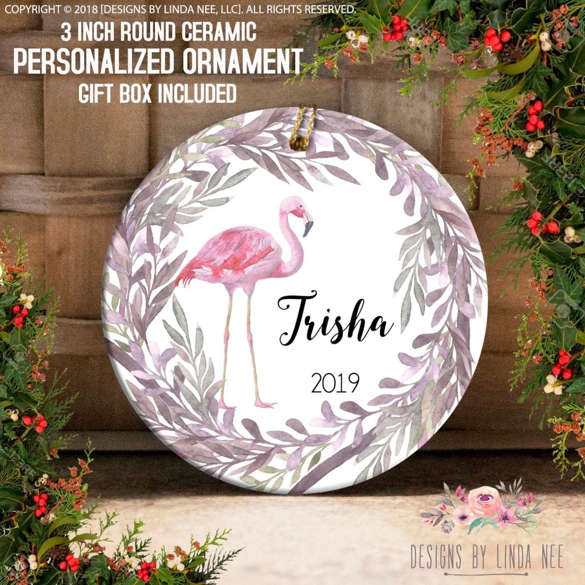 Round ceramic personalized ornament with flamingo design and 'Trisha 2019' text, surrounded by festive decorations.