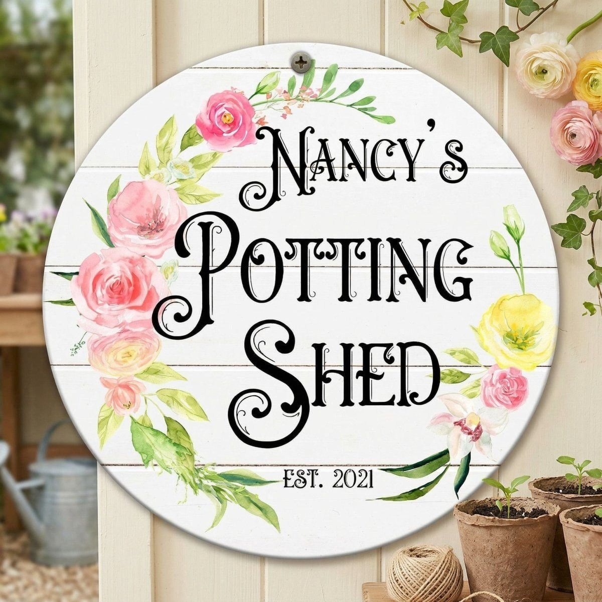 A round sign with the text "Nancy's Potting Shed" and "Est. 2021" is displayed on a wooden wall, surrounded by potted plants and flowers.
