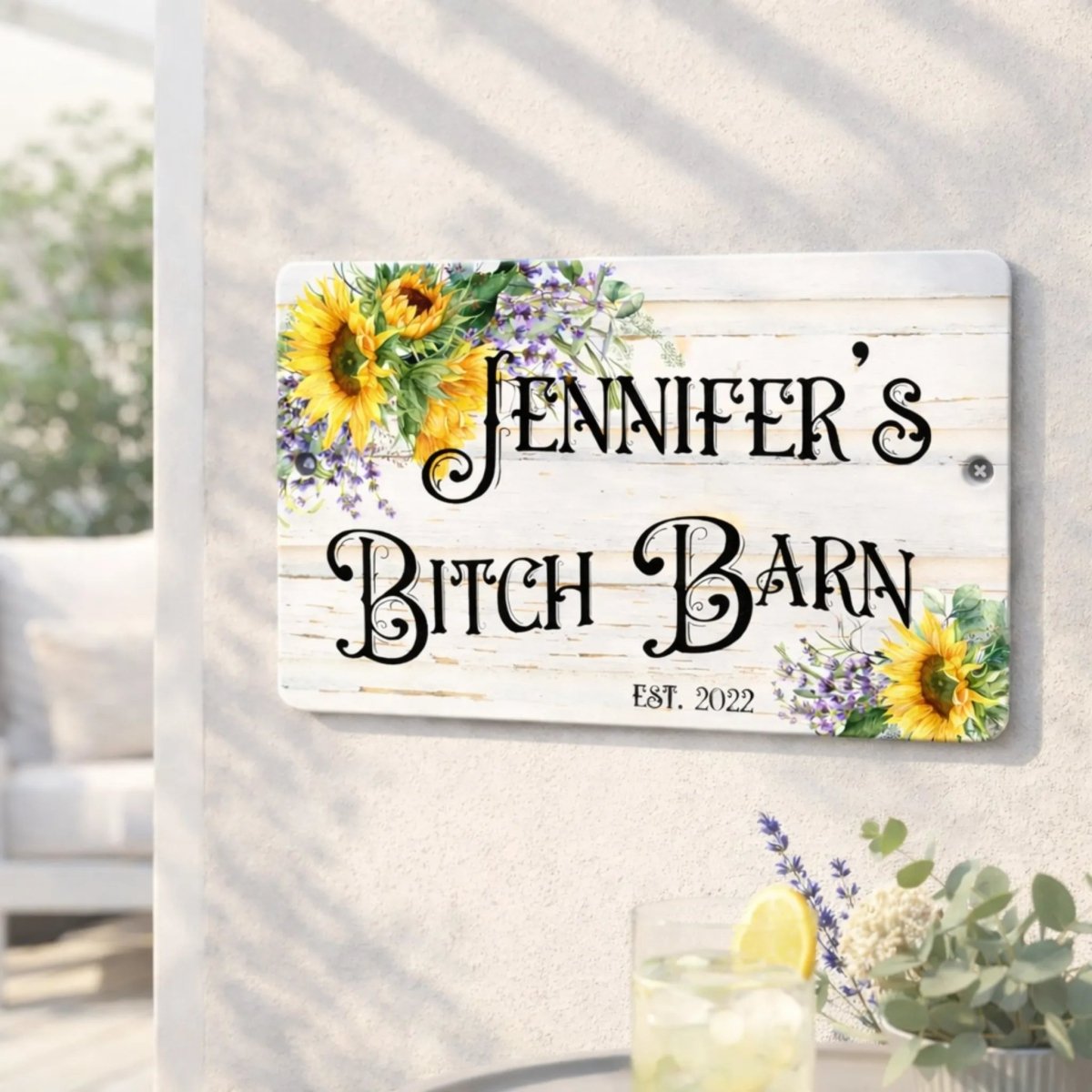 A wooden sign with a floral design and the name "Jennifer's Bitch Barn" is displayed on a wall.