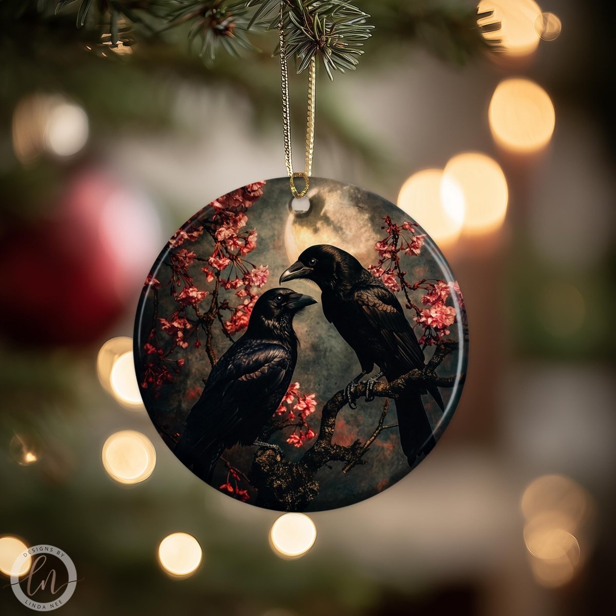A round ornament featuring two black birds perched on a branch with red flowers, set against a dark background.
