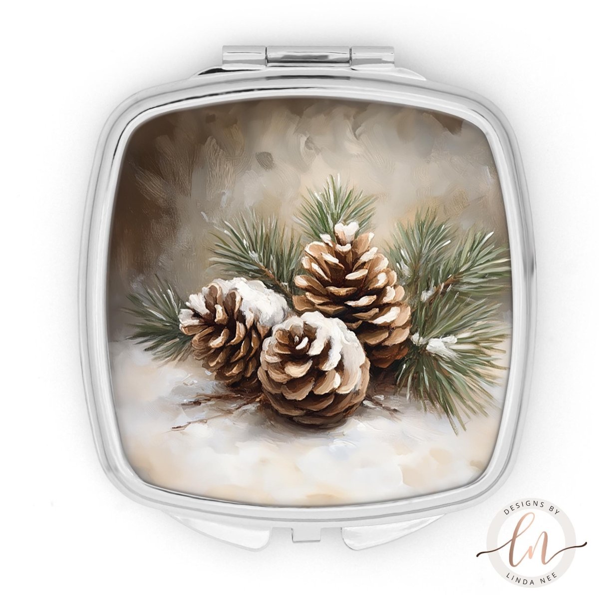 A square-shaped compact mirror with a winter scene of pine cones and pine needles on its surface.