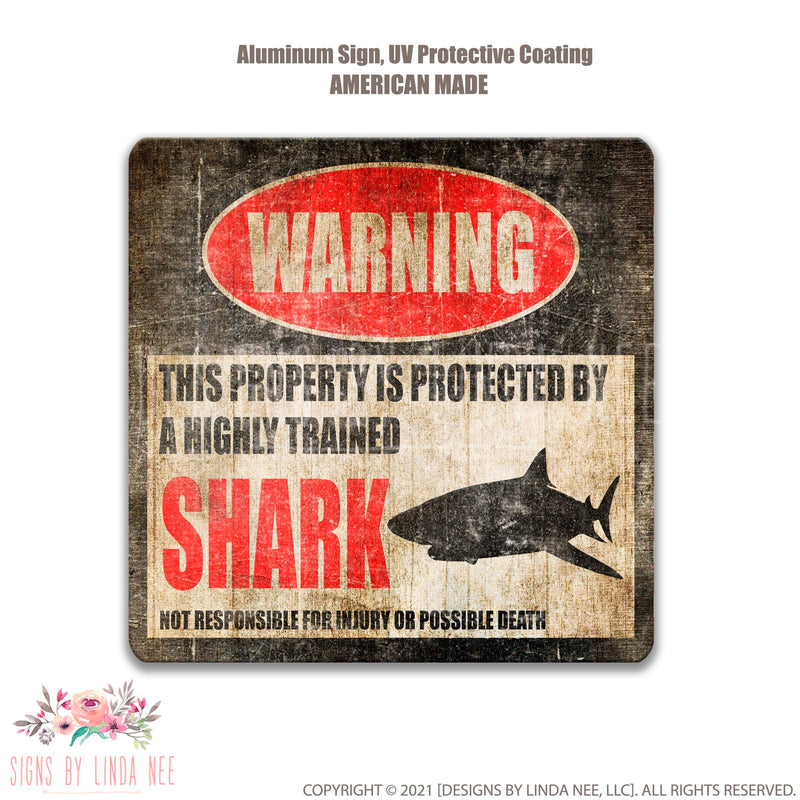 Distressed background with font saying Warning This Property is Protected by a Highly trained Shark Not responsible for injury or possible death Sign